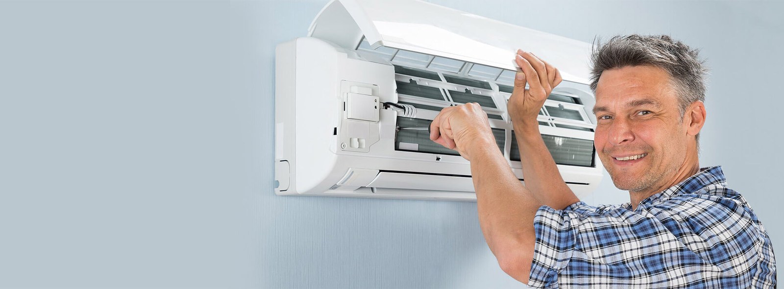 Technician servicing a wall-mounted air conditioning unit