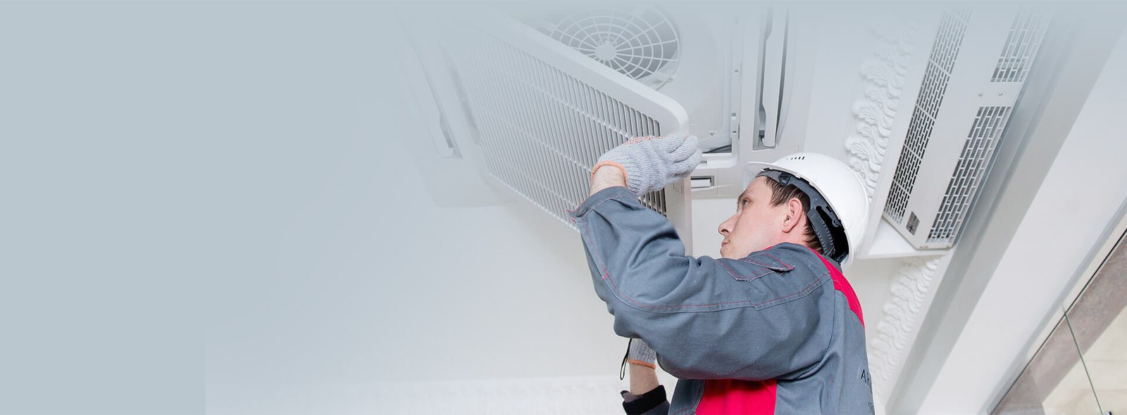 Technician servicing a ceiling-mounted air conditioning unit