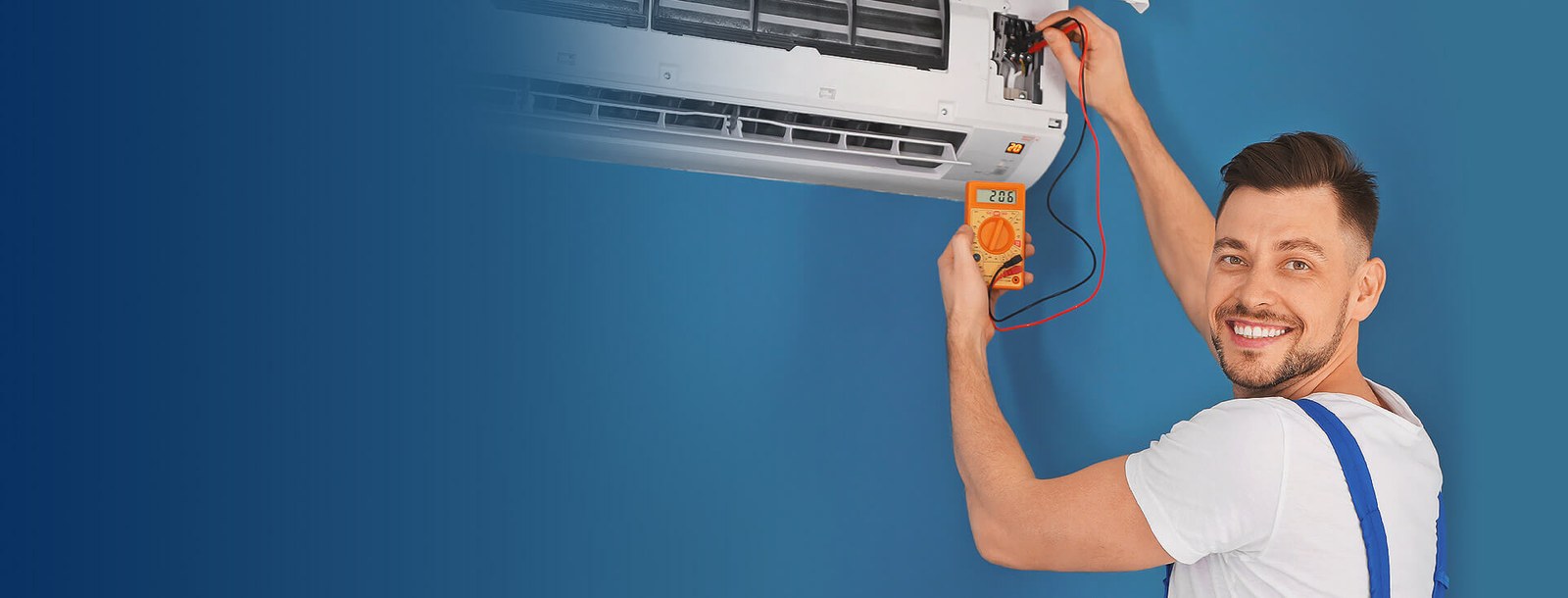 Technician testing a wall-mounted air conditioner with a multimeter