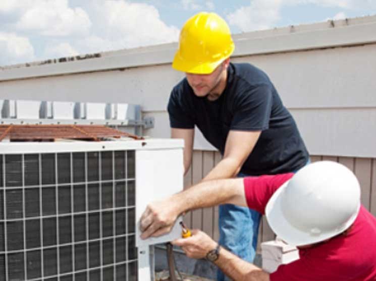 Two technicians working on an outdoor HVAC unit